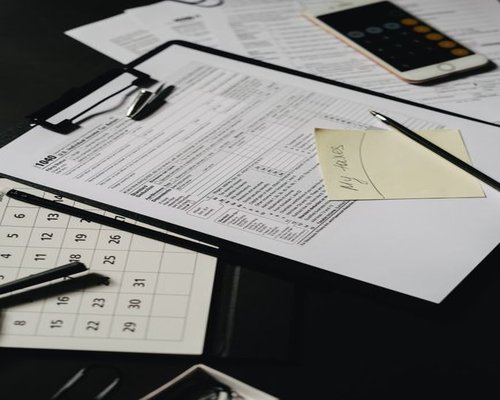 A desk organized with a household budget checklist and pen